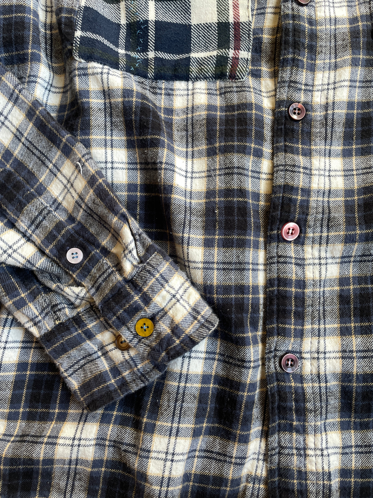 Close-up of a plaid shirt with mismatched buttons 