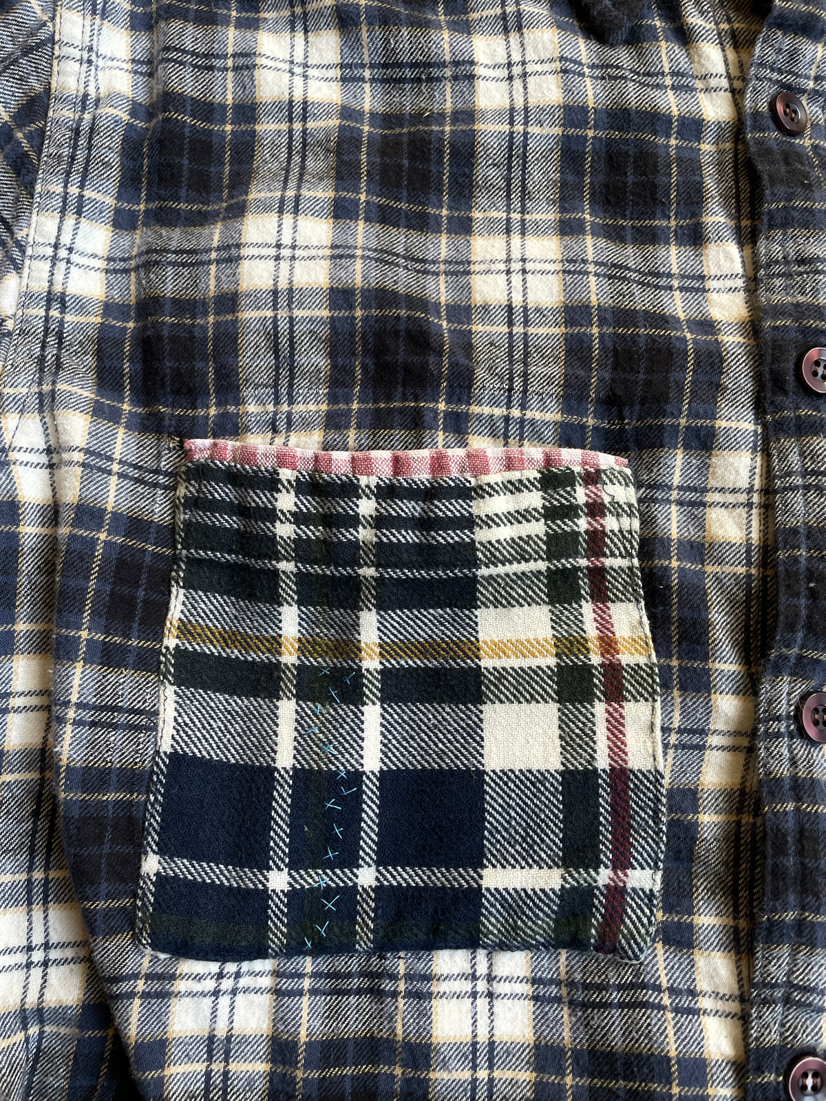 Close-up of a plaid shirt with a pocket featuring a different pattern.
